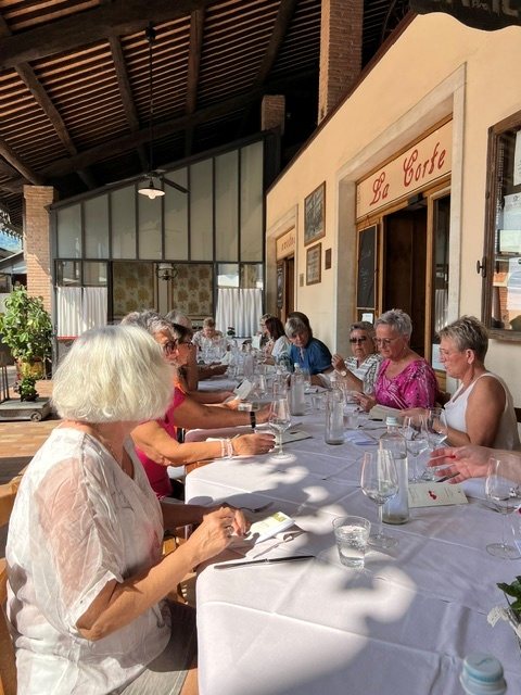 Vinturdeltakere rundt langbordet på en italiensk terrasse